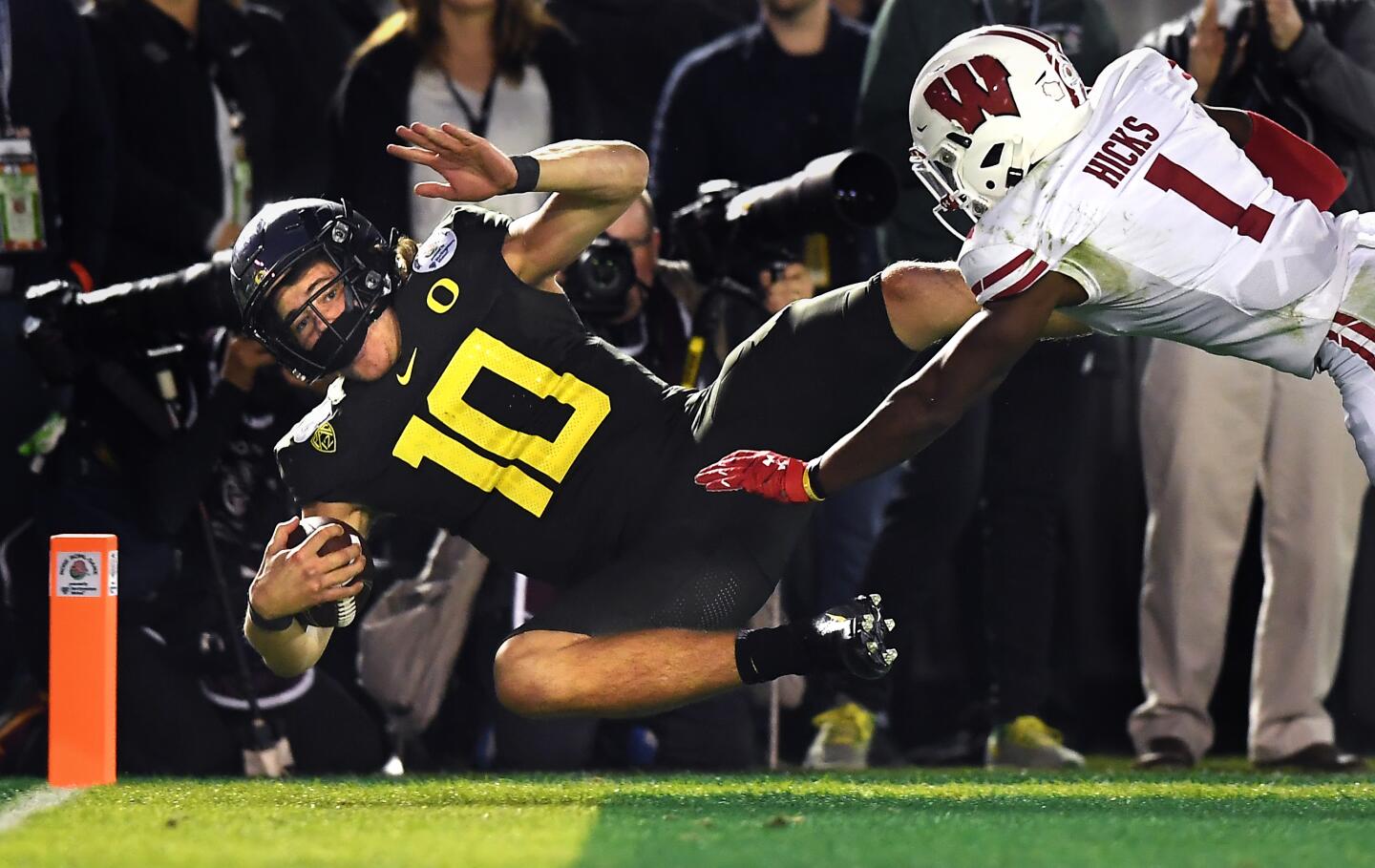 PASADENA, CALIFORNIA JANUARY 1, 2020-Oregon quarterback Justin Herbert scores the go-ahead touchdown against Wisconsin cornerback Faion Hicks in the 4th quarter at the Rose Bowl in Pasadena Wednesday. (Wally Skalij/Los Angerles Times)