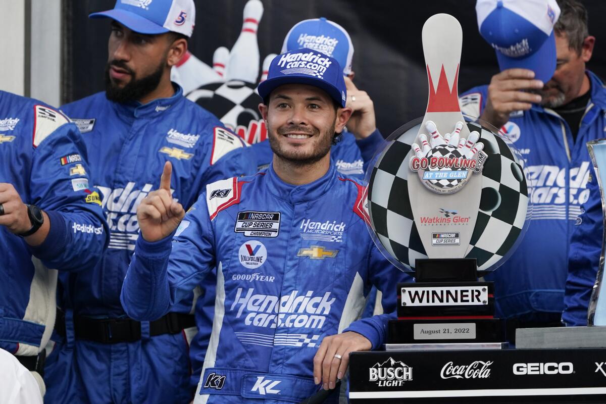 Kyle Larson poses for photos with the trophy and his team after winning a NASCAR Cup Series.