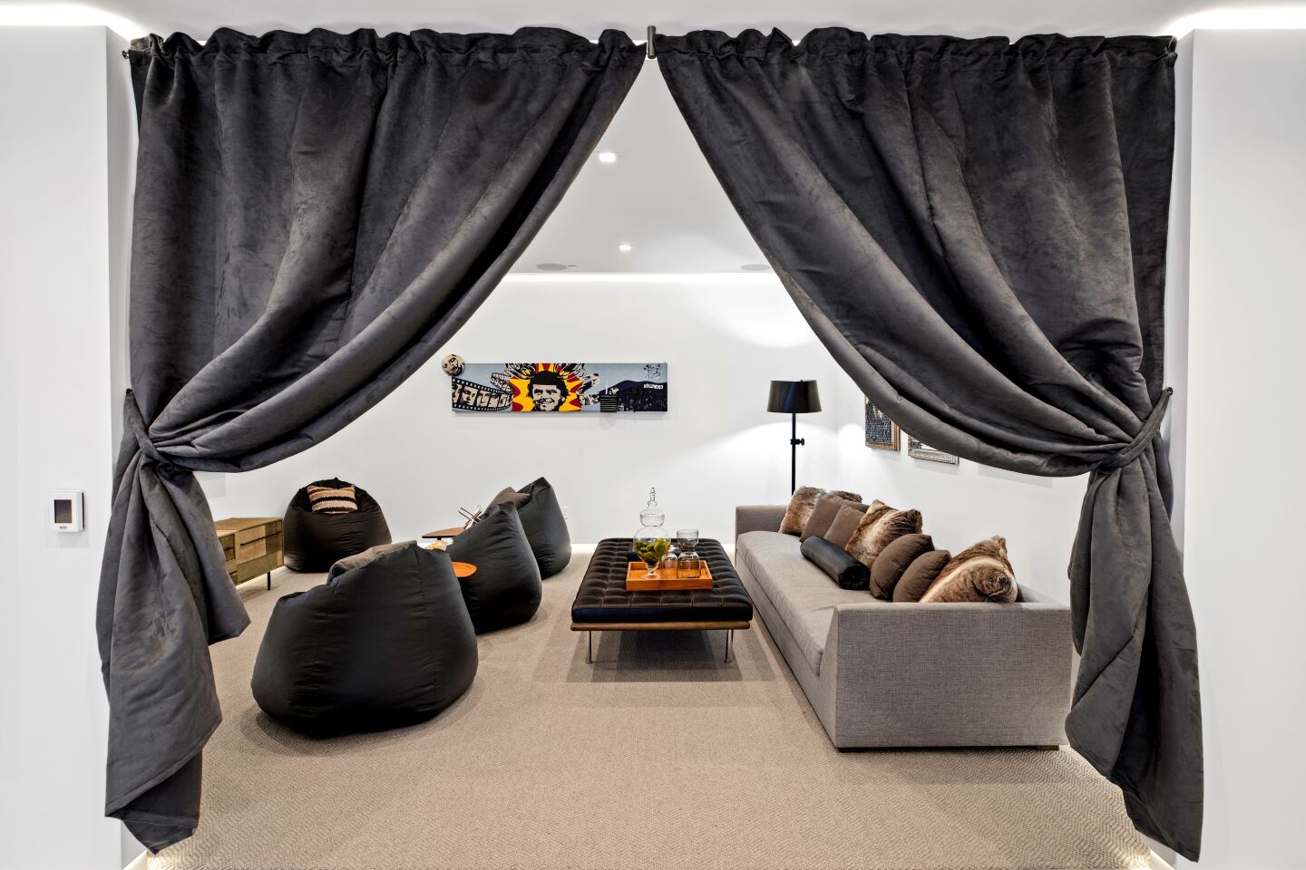 Gray curtains are pulled back on the movie room, which holds a long couch and low chairs.