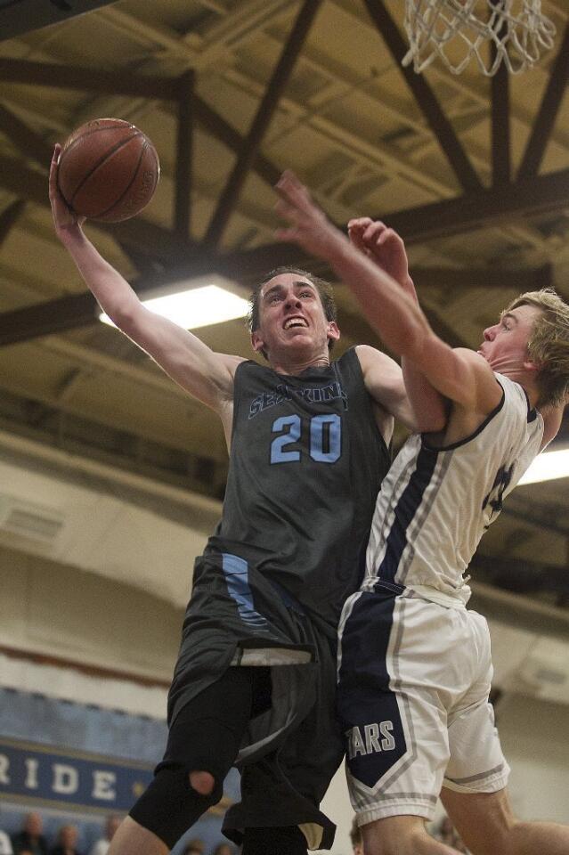 Corona del Mar High's Robby Bracho (20) goes up for a layup as Newport Harbor's Nic Sargeant attempts to block and fouls him during the Battle of the Bay on Saturday.