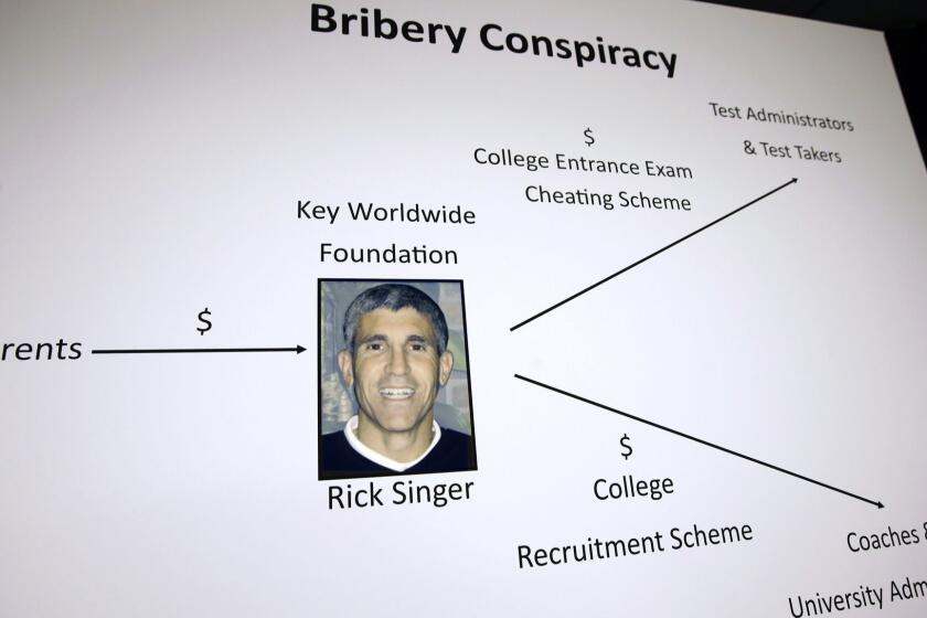 A poster containing a photo of William "Rick" Singer, founder of the Edge College & Career Network, is displayed during a news conference Tuesday, March 12, 2019, in Boston, where indictments in a sweeping college admissions bribery scandal were announced. (AP Photo/Steven Senne)