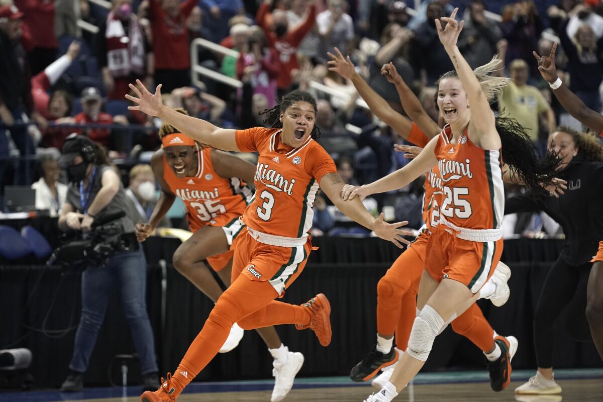 Miami forward Destiny Harden (3), forward Naomi Mbandu (35) and guard Karla Erjavec (25) react after defeating Louisville in an NCAA college basketball quarterfinal game at the Atlantic Coast Conference women's tournament in Greensboro, N.C., Friday, March 4, 2022. (AP Photo/Gerry Broome)