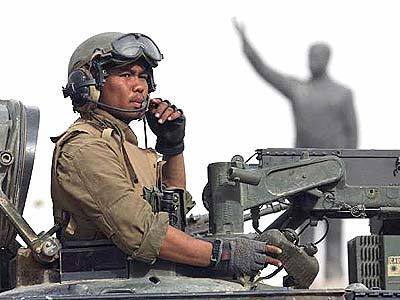 A U.S. soldier arrives at the central part of the Iraqi capital of Baghdad with the statue of Saddam Hussein seen in background.