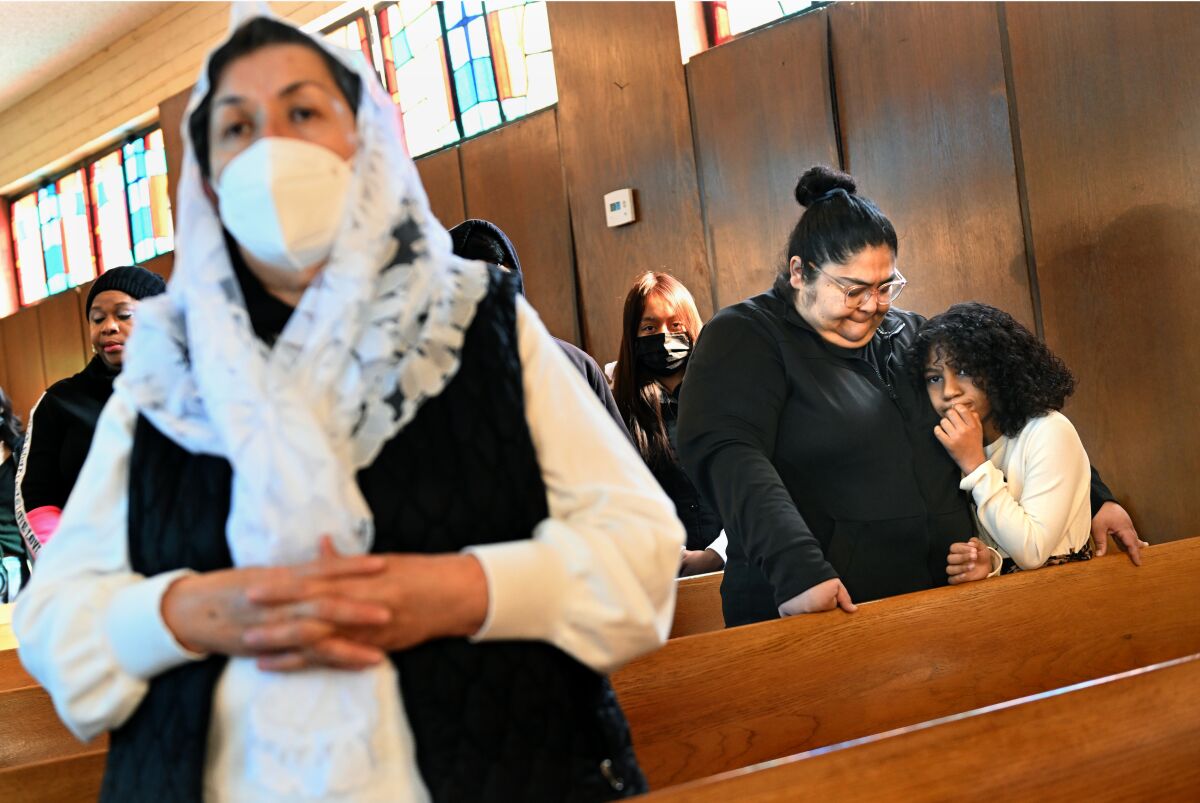 Women stand in pews and pray.