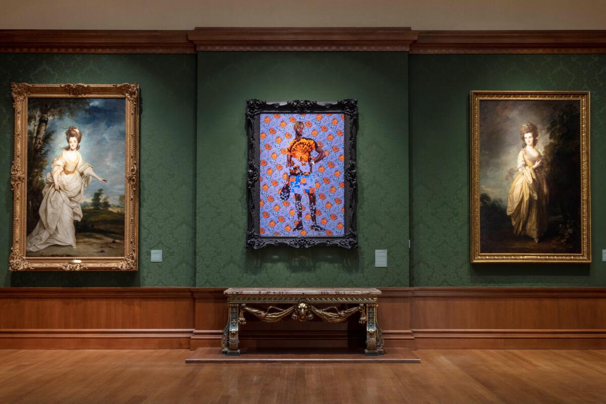 Kehinde Wiley's "Portrait of a Young Gentleman" hangs between two portraits of women in elaborate gowns