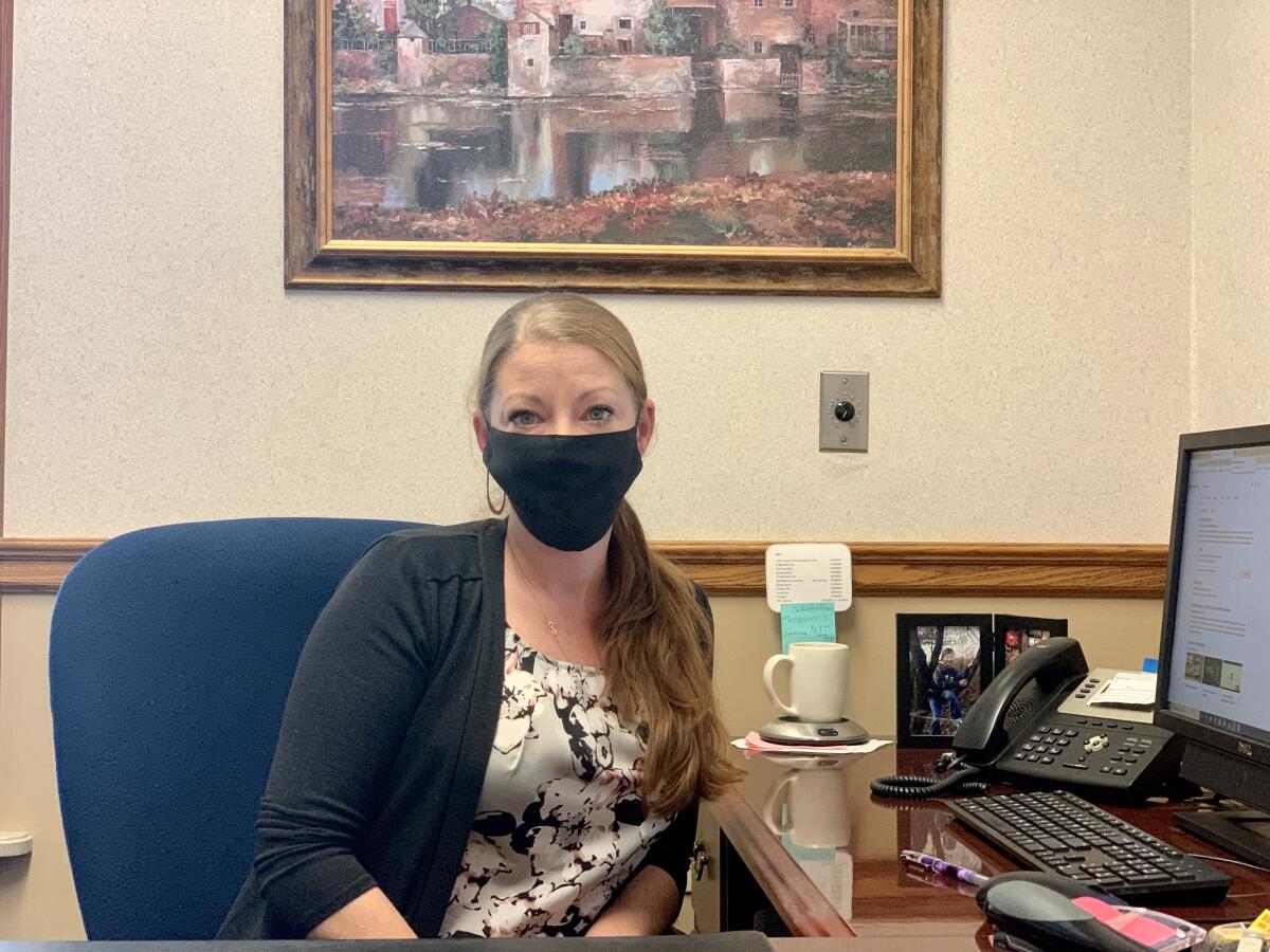 Jami Colich wears a mask while sitting at her office desk