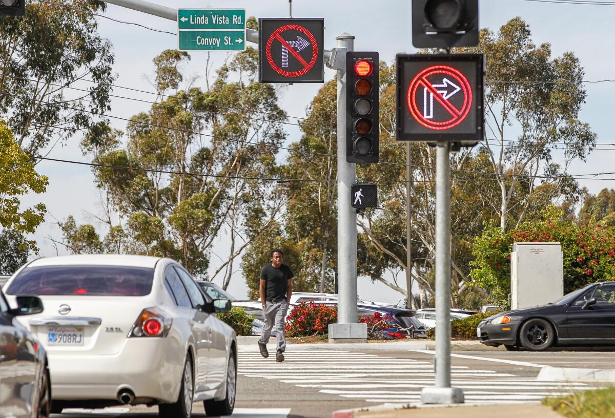 Two large digital signs displaying arrows with red lines through them warn drivers (left) on Aero Drive they can't turn right into a pedestrian crosswalk (at right) at Convoy Street on February 28, 2020 in San Diego, California.