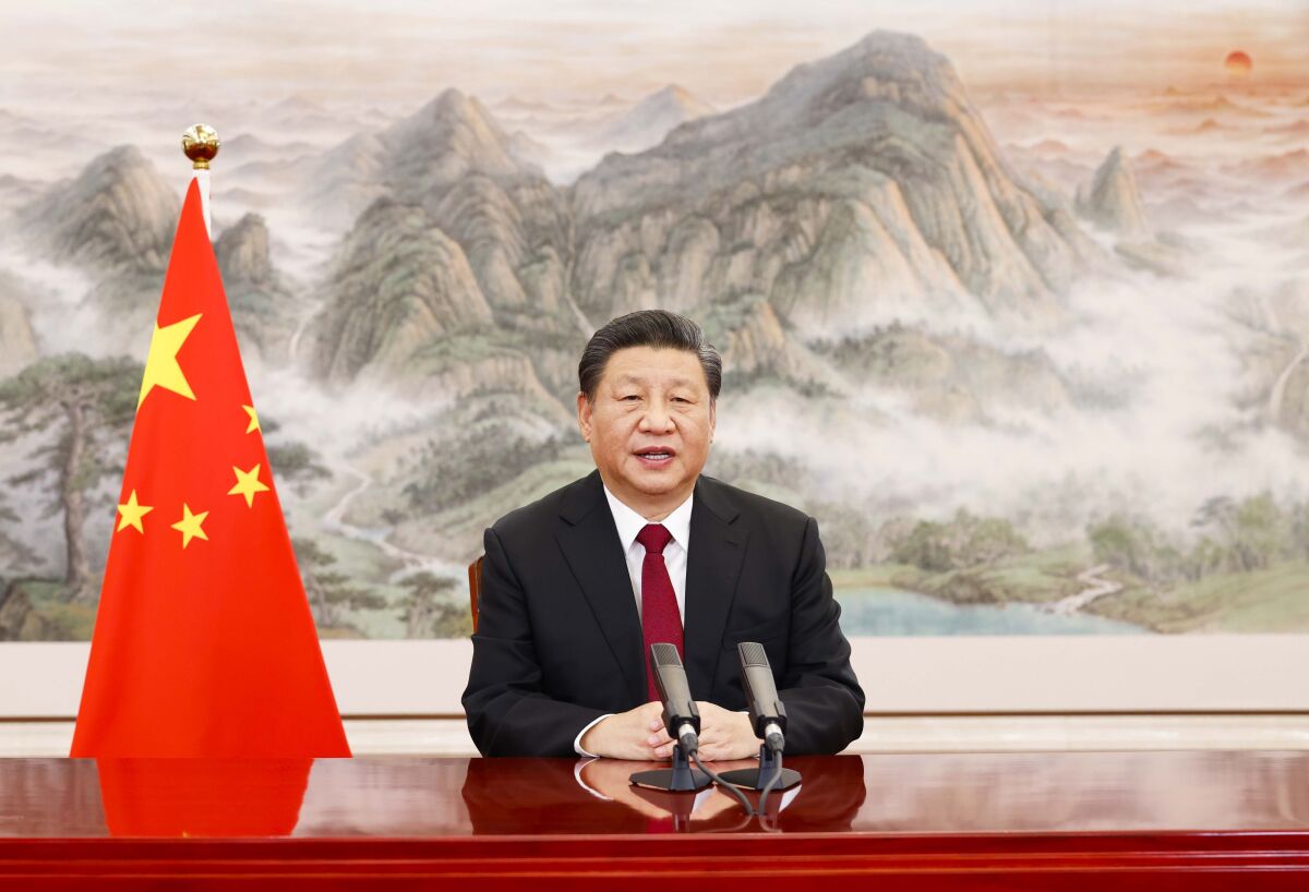 Chinese President Xi Jinping sits behind a desk and delivers a keynote address.
