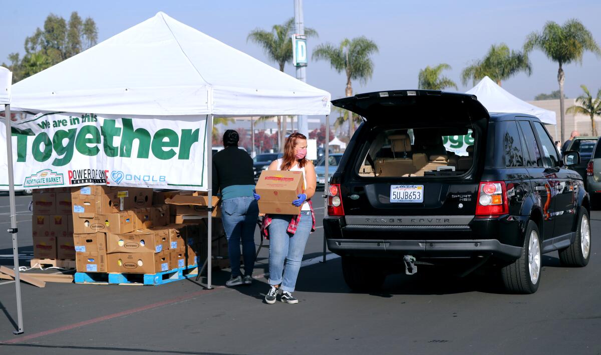 Volunteers load food into vehicles at the Power of One Foundation Thanksgiving food giveaway in Costa Mesa, Nov. 21, 2020.
