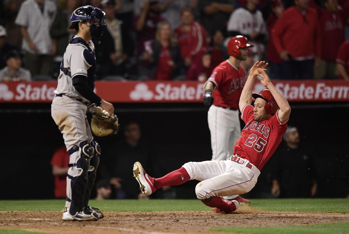 Angels' Peter Bourjos, right, scores as New York Yankees catcher Kyle Higashioka stands at the plate during the 12th inning on April 22.
