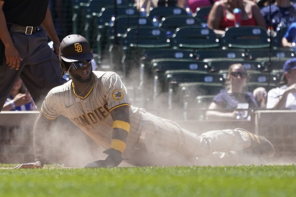 San Diego Padres' Jurickson Profar scores in a cloud of dust off a single by Manny Machado during the fourth inning of a baseball game against the Chicago Cubs Thursday, June 16, 2022, in Chicago. (AP Photo/Charles Rex Arbogast)