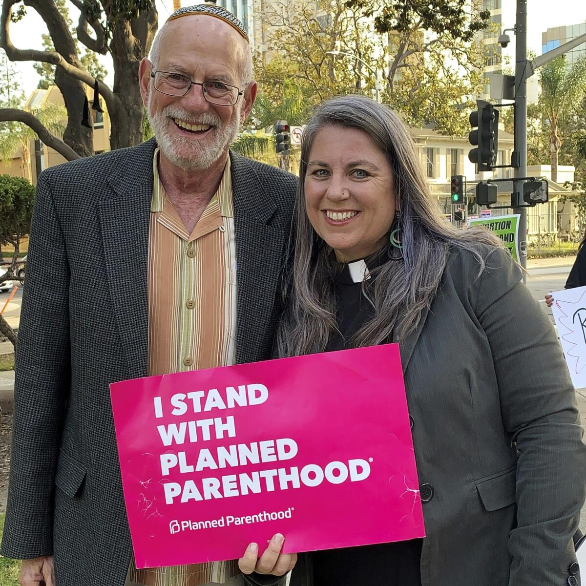 A rabbi and a minister hold a "I stand with Planned Parenthood" sign.