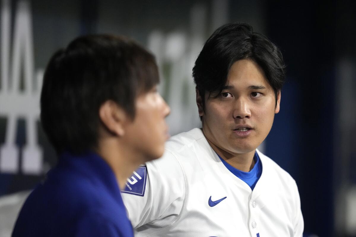Los Angeles Dodgers' designated hitter Shohei Ohtani, right, chats with his interpreter Ippei Mizuhara in the dugout.