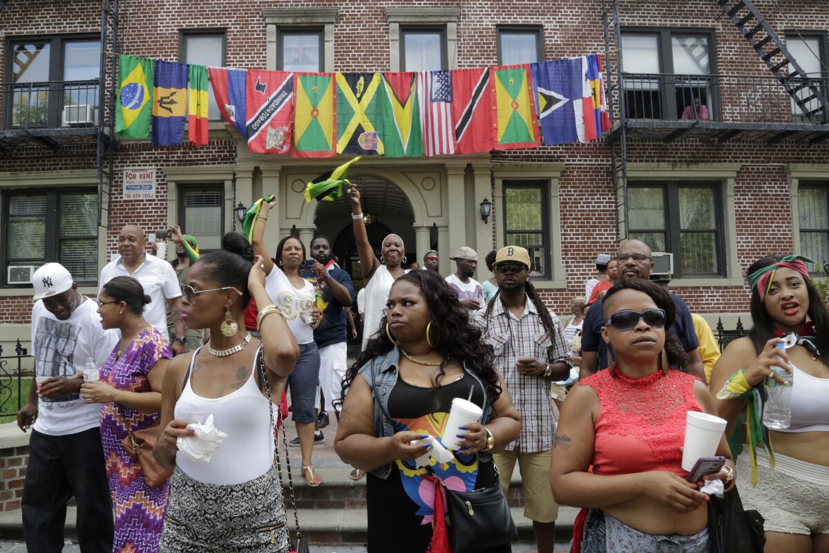 FILE - Flags representing Caribbean nations drape the front of a residential building as people gather outside to watch the annual West Indian Day Parade, celebrating Caribbean heritage, Sept. 1, 2014 in the Brooklyn borough of New York. A new report on Thursday, April 14, 2022 by Pew Research Center says a majority of Black Americans believe being Black is central to how they think about themselves and shape their identities, even as many have diverse experiences and come from various backgrounds. (AP Photo/Mark Lennihan, File)