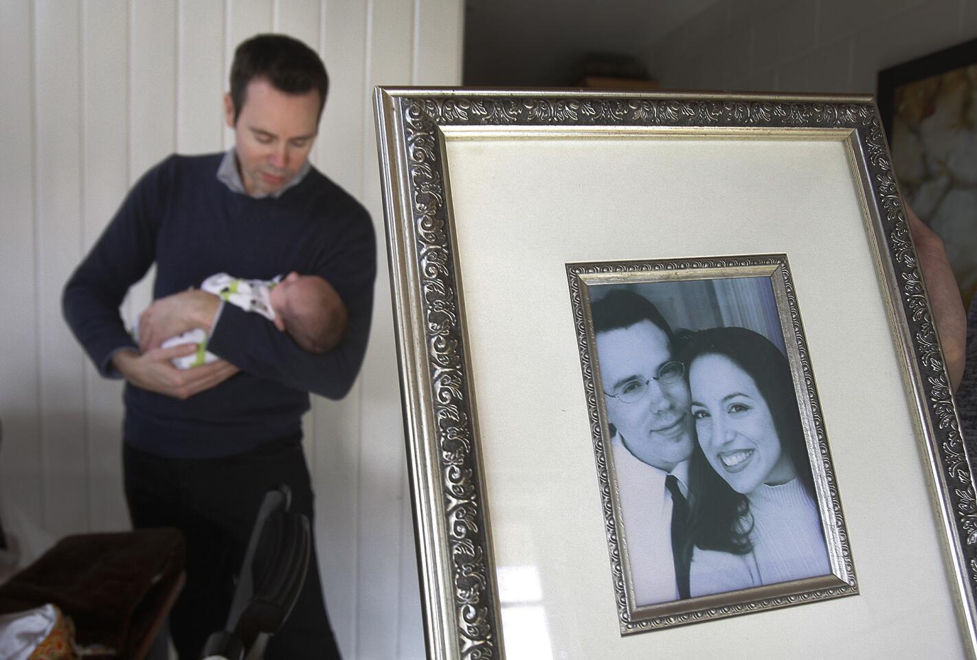 Chris Burgess, feeds his one-month-old son Colin James beyond an engagement photo of Burgess with his then-fiance Robin in 2001 at home in Burbank on Friday, Jan. 31, 2014. Robin Burgess, Chris' wife and Colin James' mom, died on January 19 after suffering a brain aneurysm on January 5, about a week after giving birth to Colin James on December 30.