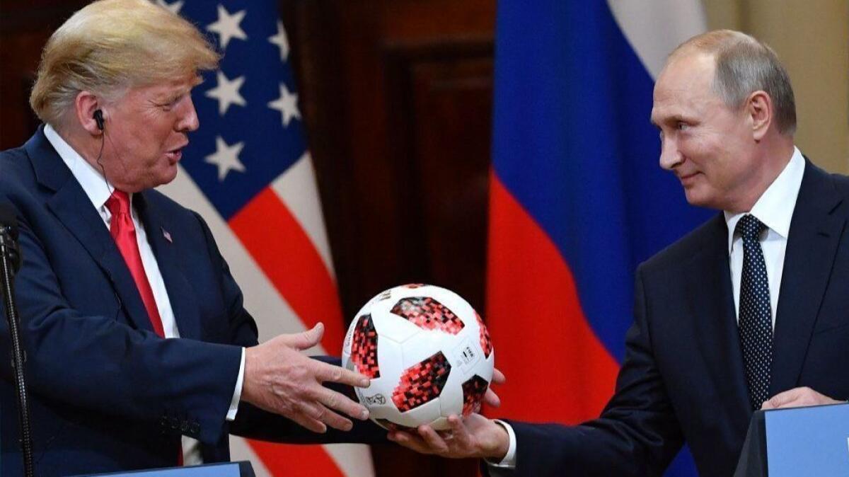 Russia's President Vladimir Putin offers a ball from the 2018 World Cup to President Trump during a joint news conference in Helsinki.