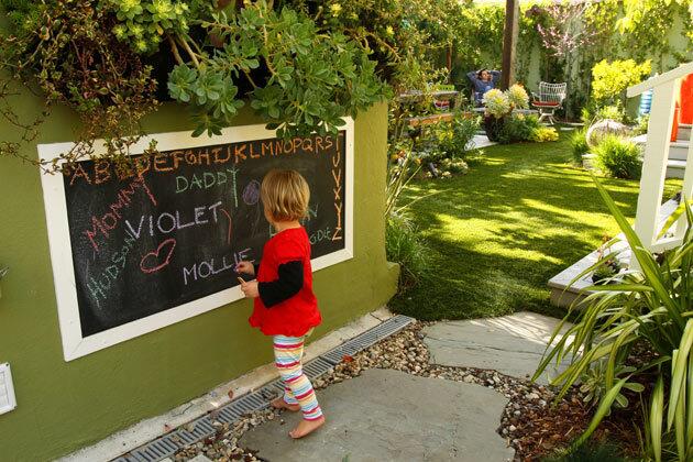 By Lisa Boone For proof that parenthood does change everything, just look at the Mar Vista garden of landscape designer Elizabeth Low. The birth of daughter Violet, now 2, inspired her to consider the question: How would the arrival of a child change the landscape. Here's a peek at Low's garden transformation and how the outdoor areas now serve as an extension of the 900-square-foot house. Pictured here: Low's daughter, Violet Cash, 2, draws on the outdoor chalkboard designed by her mother, who rolled chalkboard paint onto the wall and added a painted wood frame. The girl's father, David Cash, is in the background, by the fire pit.