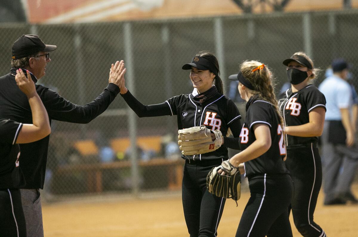 Huntington Beach coach Jeff Forsberg high fives Kayla Hayashi after she closed out the fifth inning in a win over Marina.