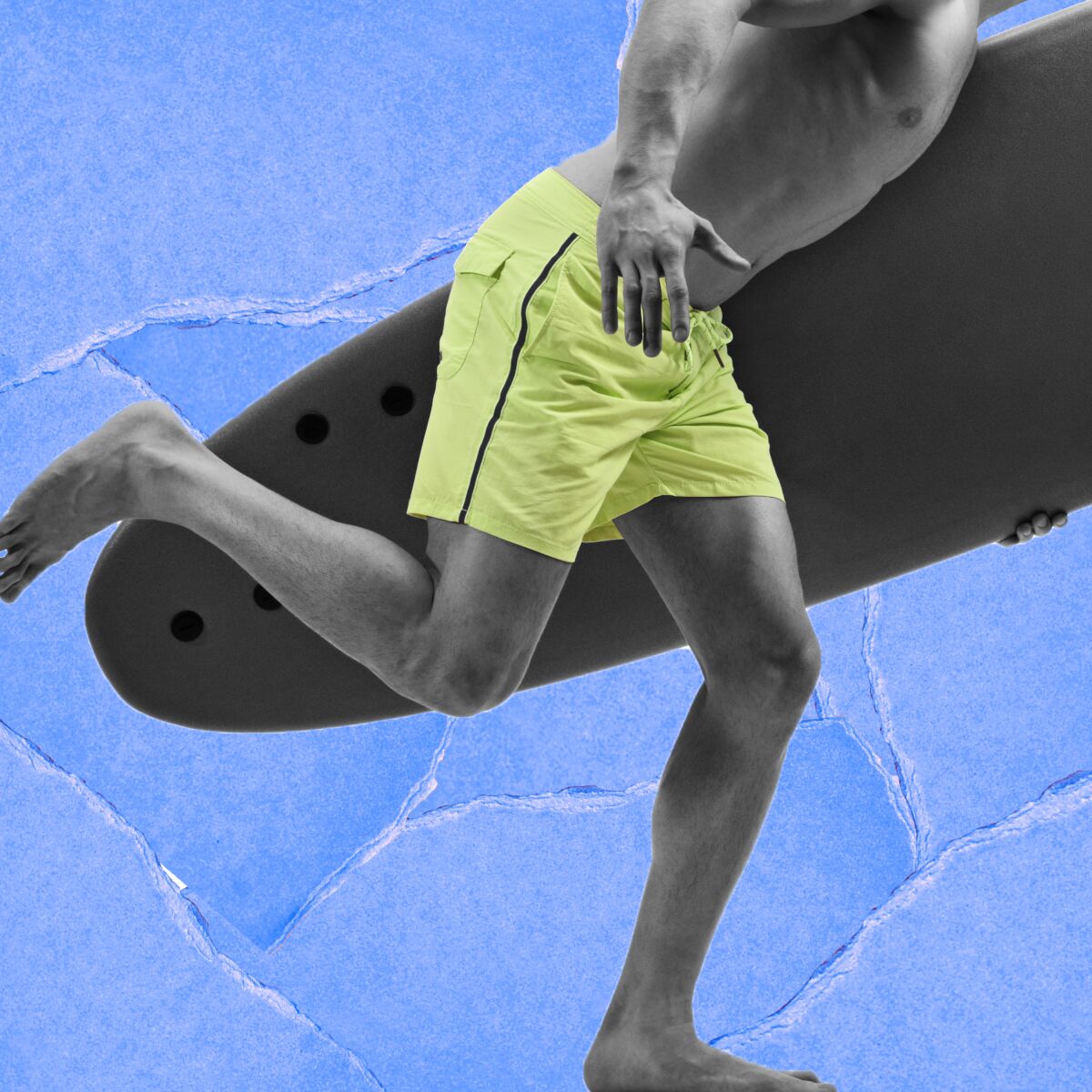 Closeup of the torso and legs of a person in board shorts carrying a surfboard and running.