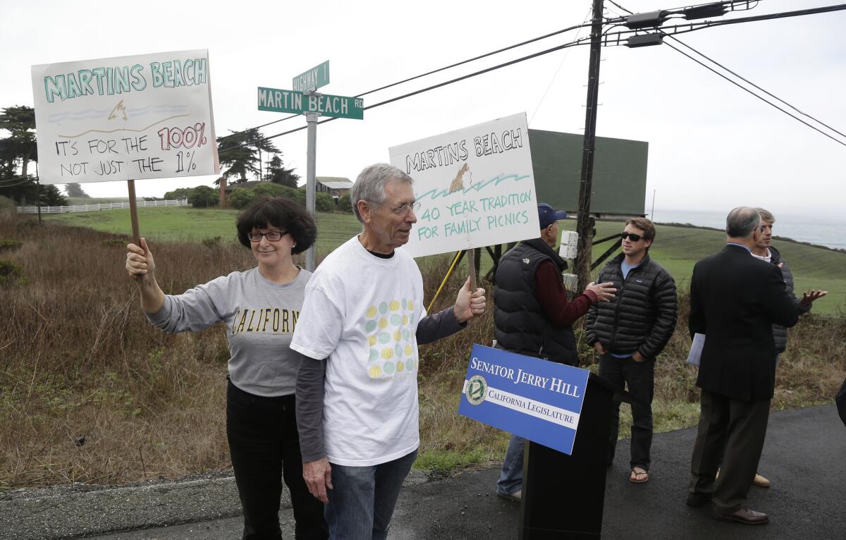 Julie Graves, left, of Albany, Calif., and Chris Adams, second from left, of Berkeley, hold up signs Feb. 10 in support of a beach access bill that Democratic state Sen. Jerry Hill introduced near Martin's Beach in Half Moon Bay.