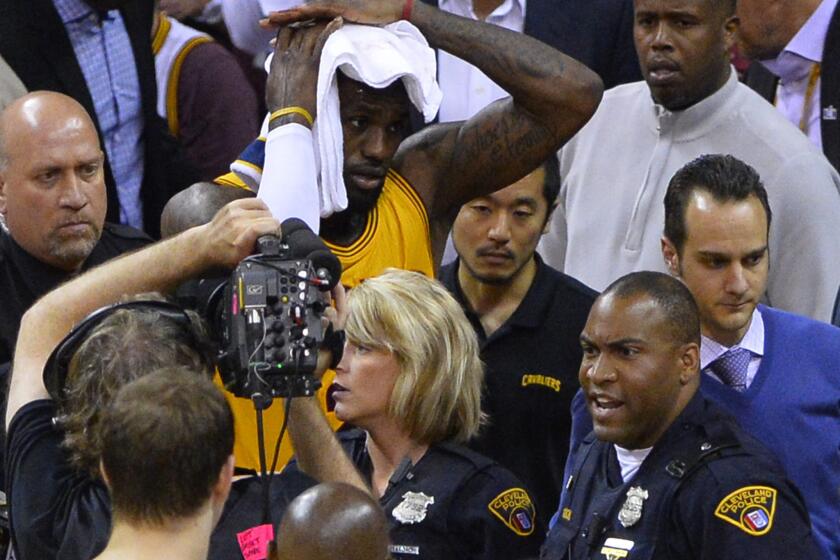 Cavaliers forward LeBron James holds a towel to his head after falling into a cameraman during Game 4 of the NBA Finals on Thursday in Cleveland.
