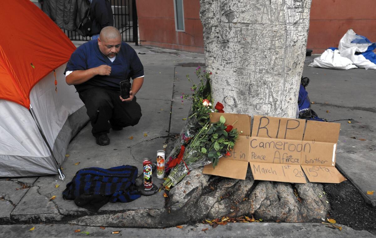 Fernando Avila kneels at the makeshift memorial near the site of Sunday's officer-involved shooting in downtown L.A.'s skid row.