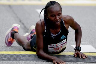 LOS ANGELES, CALIF. - MAR. 19, 2023. Stacy Ndiwa of Kenya collapses after crossing the finish line to win the women's elite Los Angeles Marathon on Sunday, Mar. 19, 2023 (Luis Sinco / Los Angeles Times)