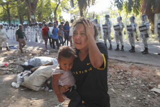 A migrant who had been part of a caravan moves away from Mexican guarsdmen near Tapachula on Thursday. Troops and immigration agents stopped the caravan and transported the migrants to a detention center in the nearby city of Tapachula.