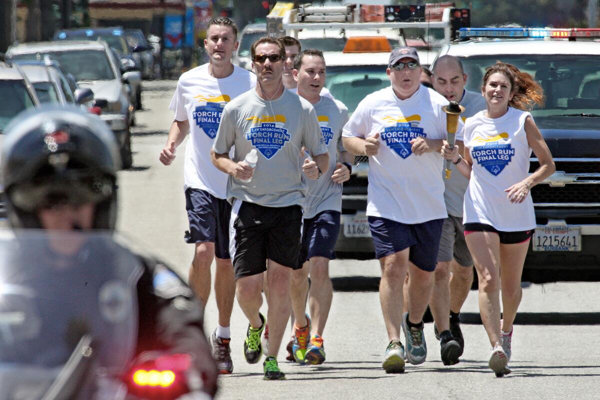 Burbank police personnel run the torch down Glenoaks Blvd. for the Burbank leg of the annual Law Enforcement Special Olympic Torch Run on Wednesday, June 4, 2014.