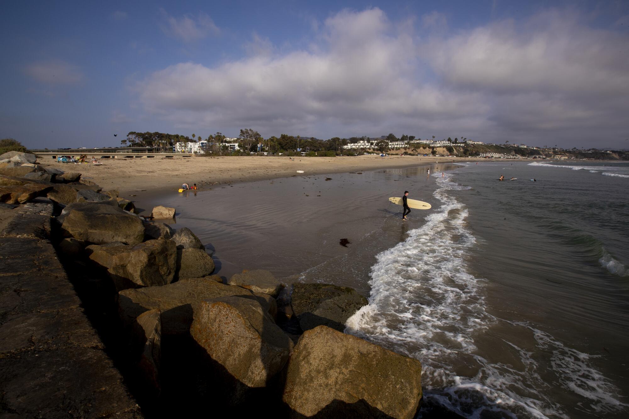 A surfer heads out near the location of a proposed desalination plant