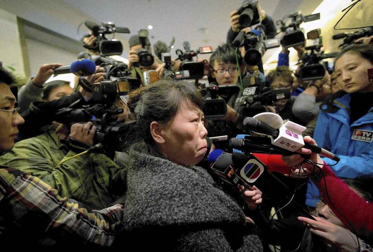 In Beijing, a relative of passengers aboard the missing Malaysia Airlines plane is surrounded by journalists as she answers questions about how families are being compensated while they await news on Flight 370.