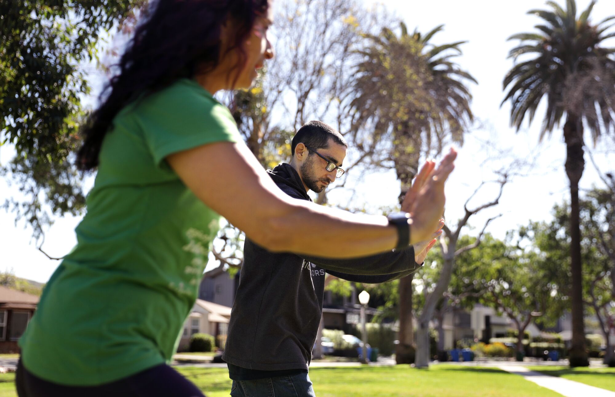 A woman and man do tai chi outside 