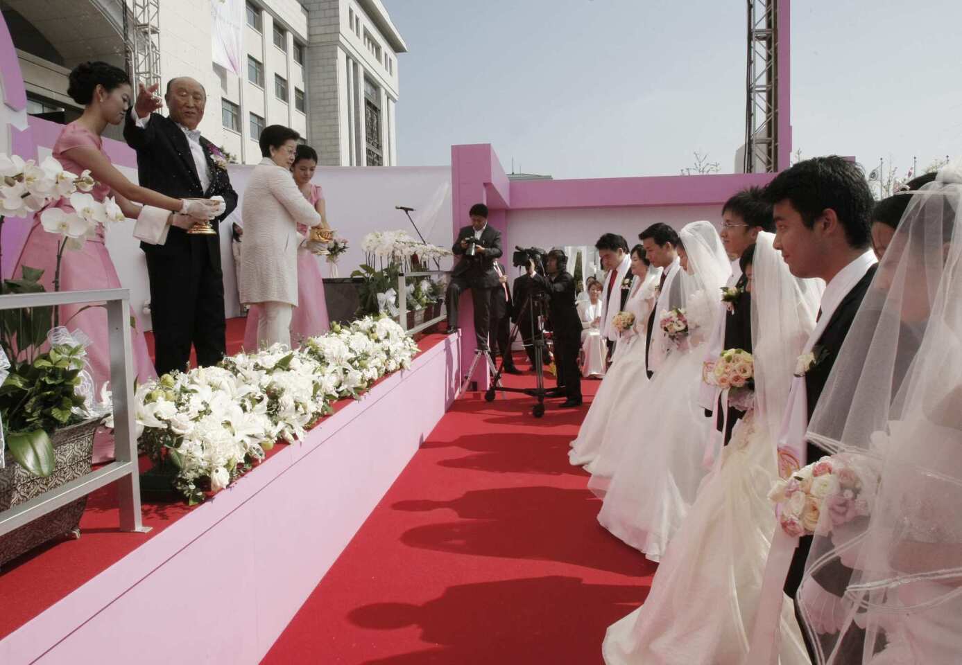 The Rev. Sun Myung Moon, top second left, sprinkles holy water during a mass wedding ceremony in Asan, South Korea, as about 7,200 South Korean and foreign couples exchange or reaffirm marriage vows.