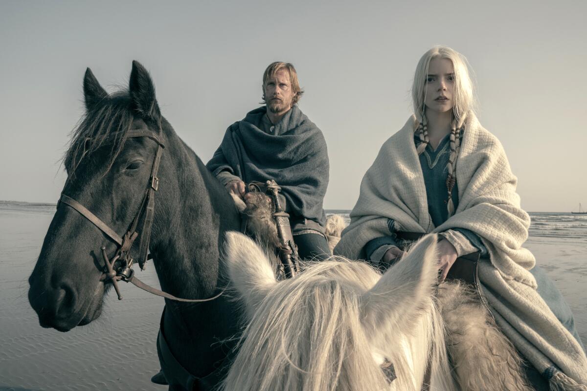 A man and a woman each on horseback in water.