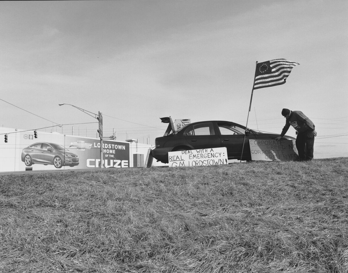 A 2019 black and white photo of a man protesting the closure of an auto plant