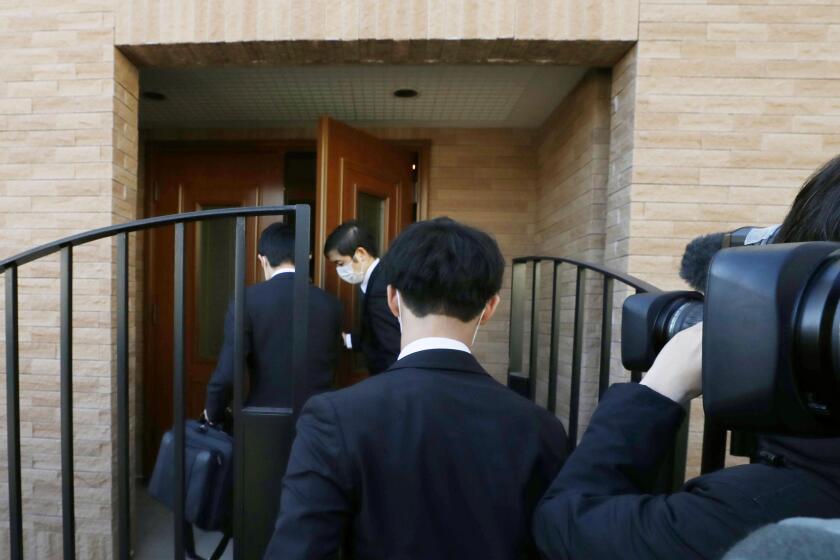 Prosecutors enter the Tokyo home of former Nissan Chairman Carlos Ghosn during a raid on Thursday.