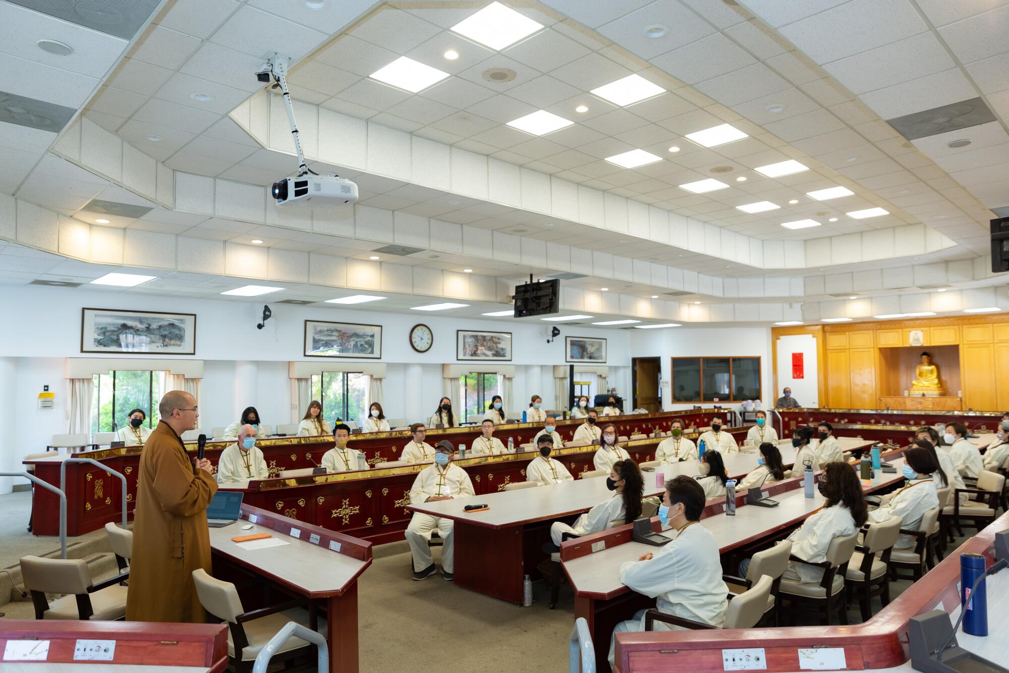 A monk speaks to a classroom of students. 