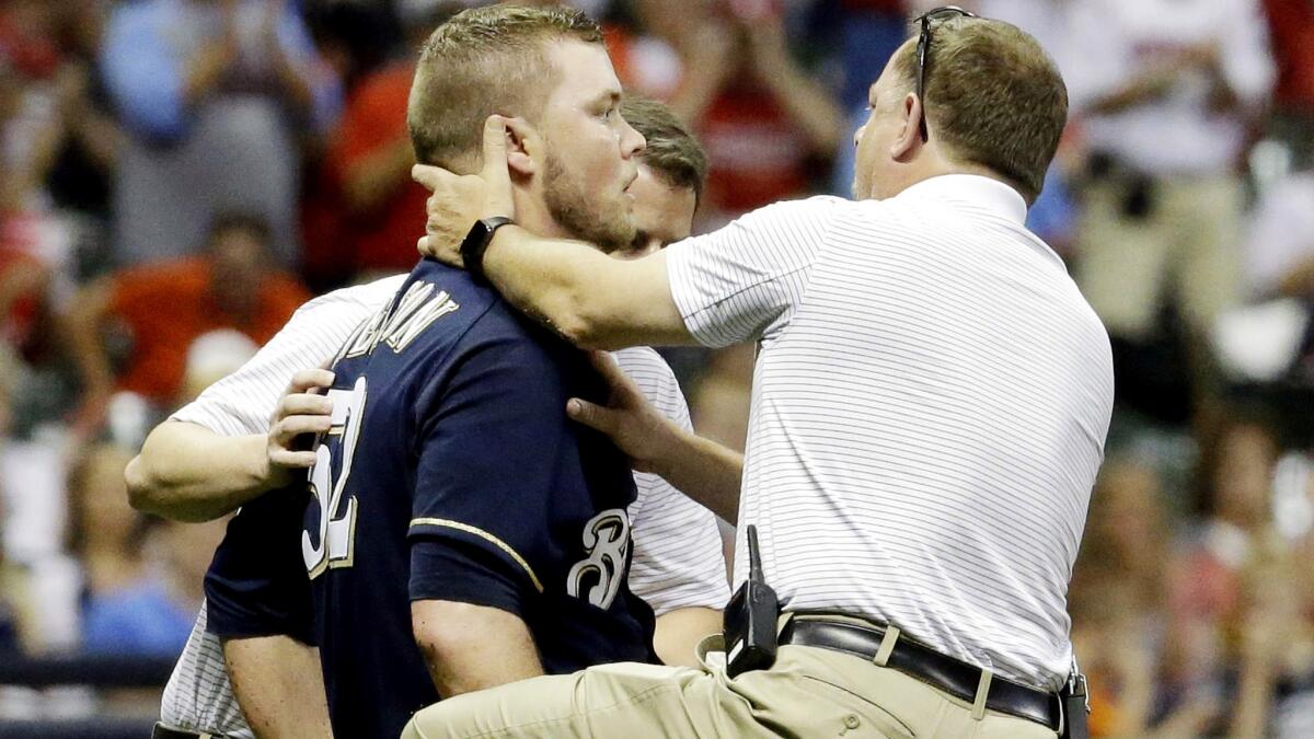 Brewers starter Jimmy Nelson is examined by a trainer after getting hit in the head by a line drive off the bat of St. Louis' Thomas Pham in the third inning Thursday night.