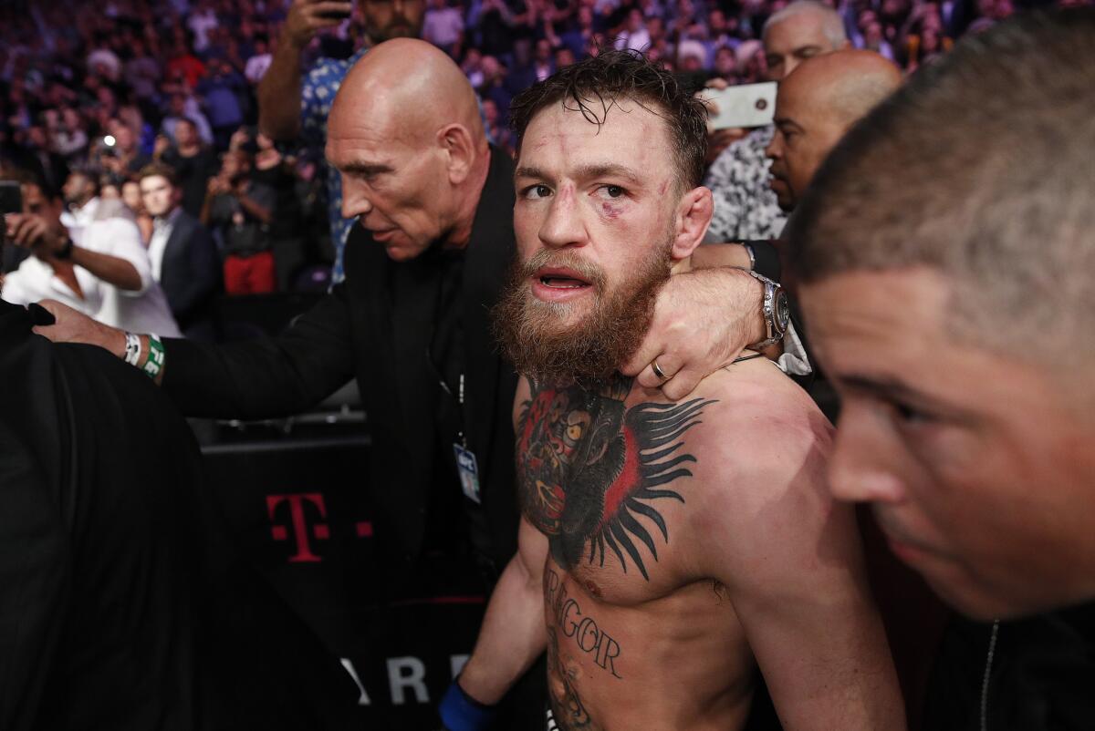 Conor McGregor is escorted from the cage area after his loss.