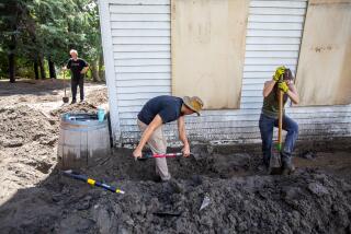 OAK GLEN, CA - AUGUST 21, 2023: Workers shovel mud outside the tavern at Riley's Farm mud and debris in Yucaipa, CA August 21, 2023. There were mudflows and flooding overnight in the Oak Glen community from tropical storm Hillary. (Francine Orr/ Los Angeles Times)