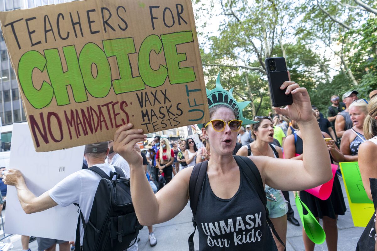 A female protester holds up a sign and a phone at a rally.
