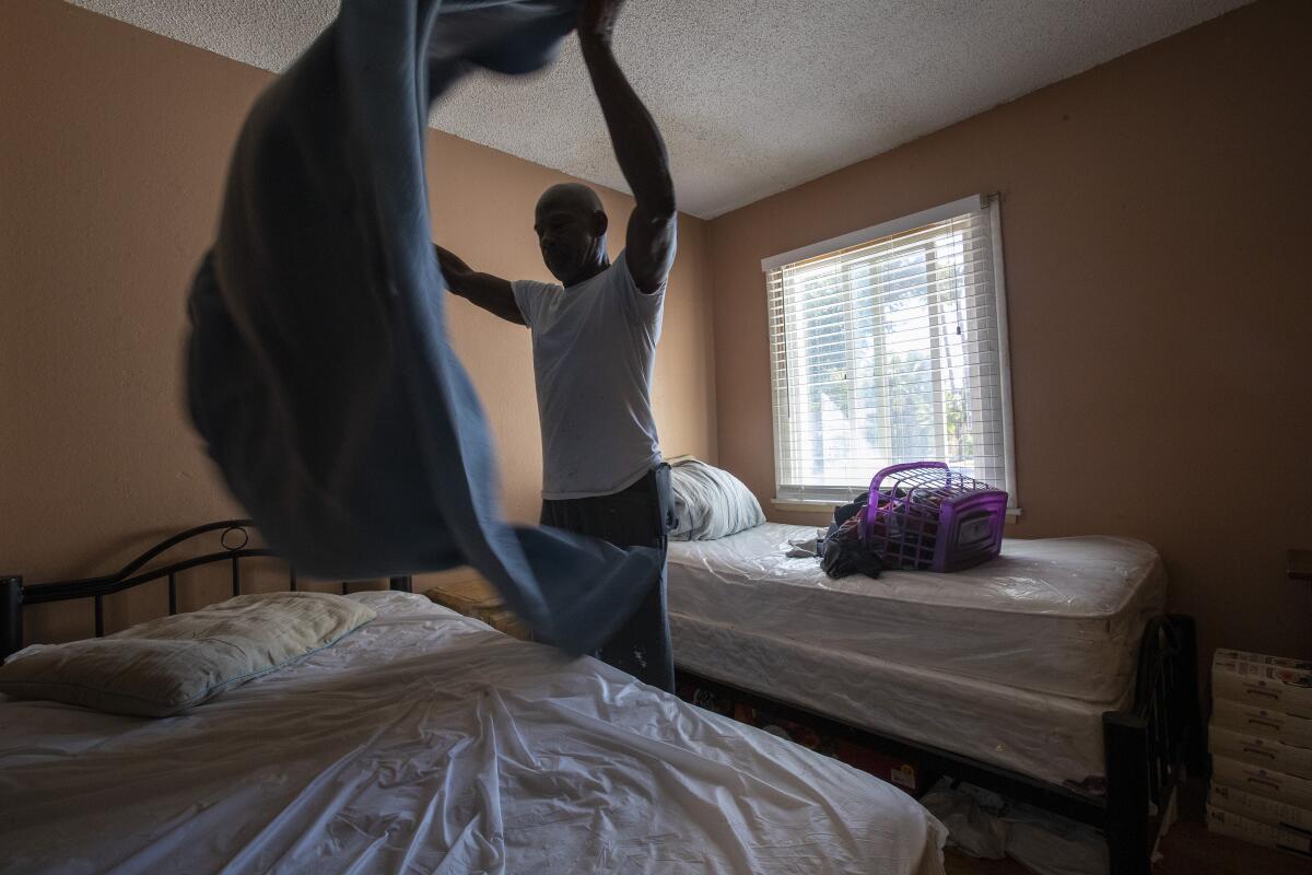 Sam Blake makes a bed after doing laundry at the Blake Home in Sylmar.