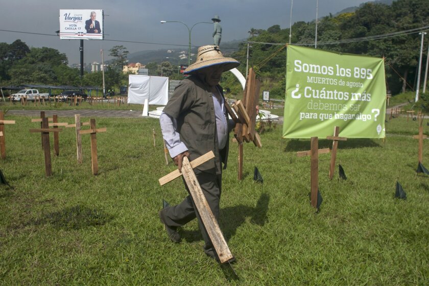 A city employee removes wooden crosses that were placed in a plaza by organizations protesting against the government inaction over the alarming murder rate in San Salvador, El Salvador, on Sept. 1.