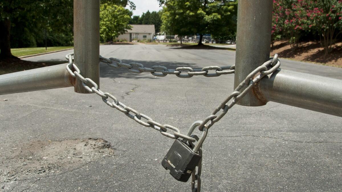 The locked gate of the Glenridge Community Pool in Winston-Salem, N.C. Adam Bloom, a white man who challenged a black family's use of a gated pool in a North Carolina neighborhood, has not only resigned from the homeowner's association board - he's also lost his job.