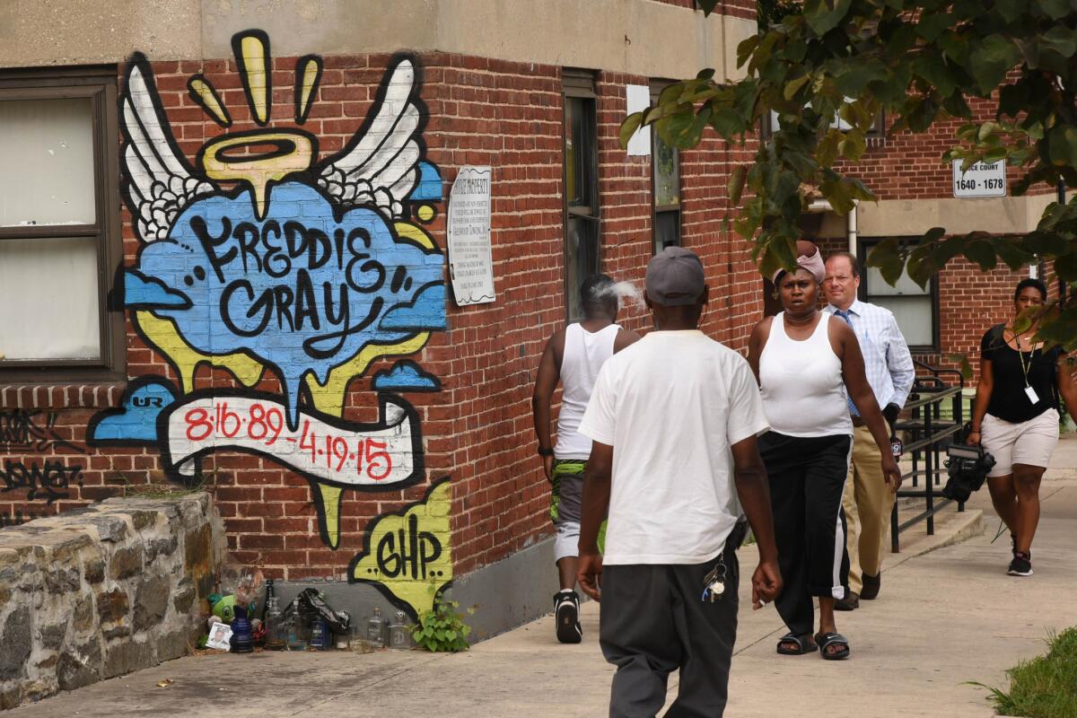 People in Baltimore walk past the site where Freddie Gray was arrested. His death in police custody helped spark a sweeping pact to revamp the department.