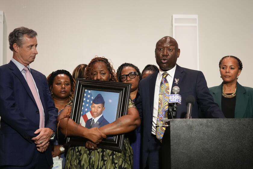 CORRECTS SERVICE BRANCH TO U.S. AIR FORCE INSTEAD OF U.S. NAVY - Chantemekki Fortson, mother of Roger Fortson, a U.S. Air Force senior airman, holds a photo of her son during a news conference regarding his death, along with family and attorney Ben Crump, right, and Brian Bar, left, Thursday, May 9, 2024, in Fort Walton Beach, Fla. Fortson was shot and killed by police in his apartment, May 3, 2024. Far right is attorney Natalie Jackson. (AP Photo/Gerald Herbert)