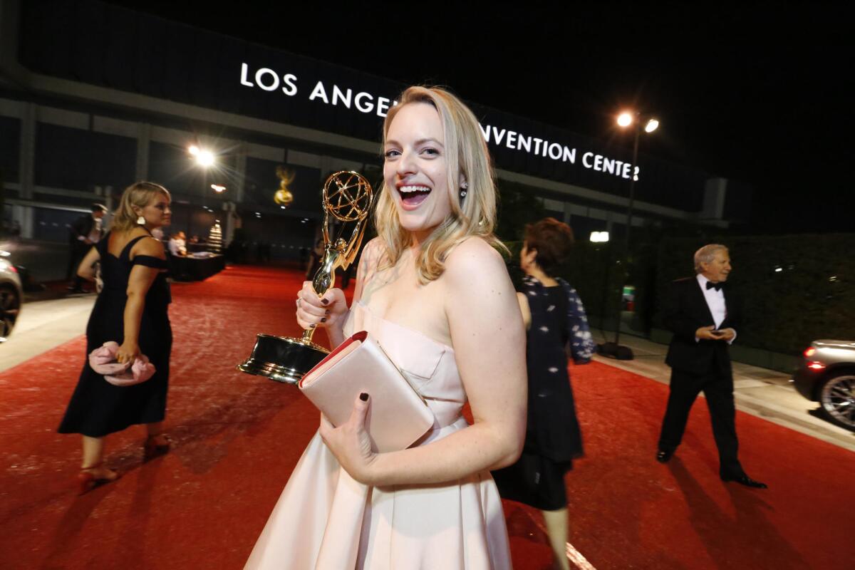 "The Handmaid's Tale's" Elisabeth Moss holds up her Emmy Awards out side the Los Angeles Convention Center.