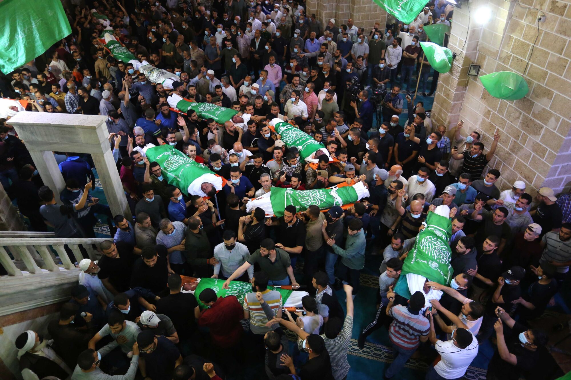 Bodies wrapped in Palestinian flags are carried by crowds