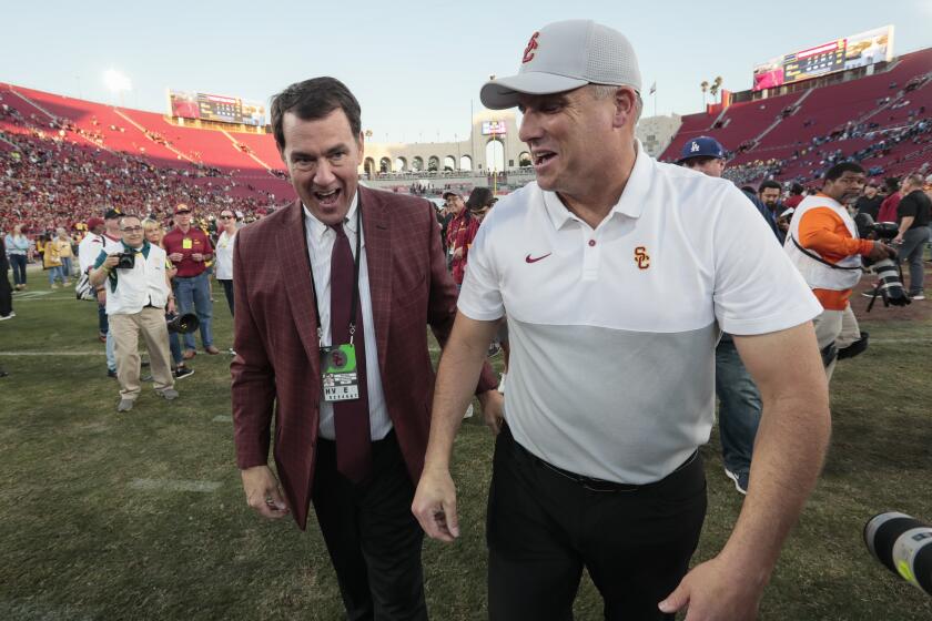LOS ANGELES, CA, SATURDAY, NOVEMBER 23, 2019 - USC head coach Clay Helton and Athletic Director Mike Bohn share a laugh together at midfield after a 52-35 win over UCLA at the Coliseum. (Robert Gauthier/Los Angeles Times)