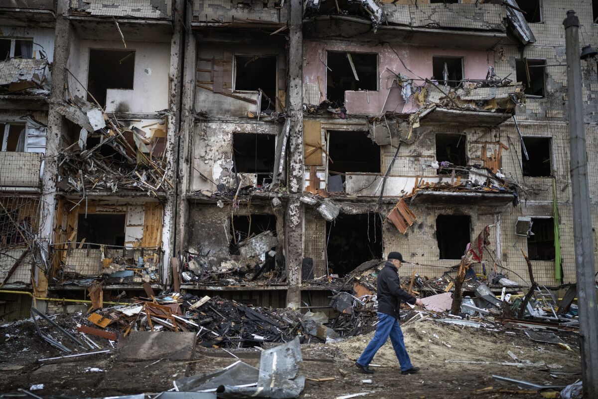 A man walks past a damaged building